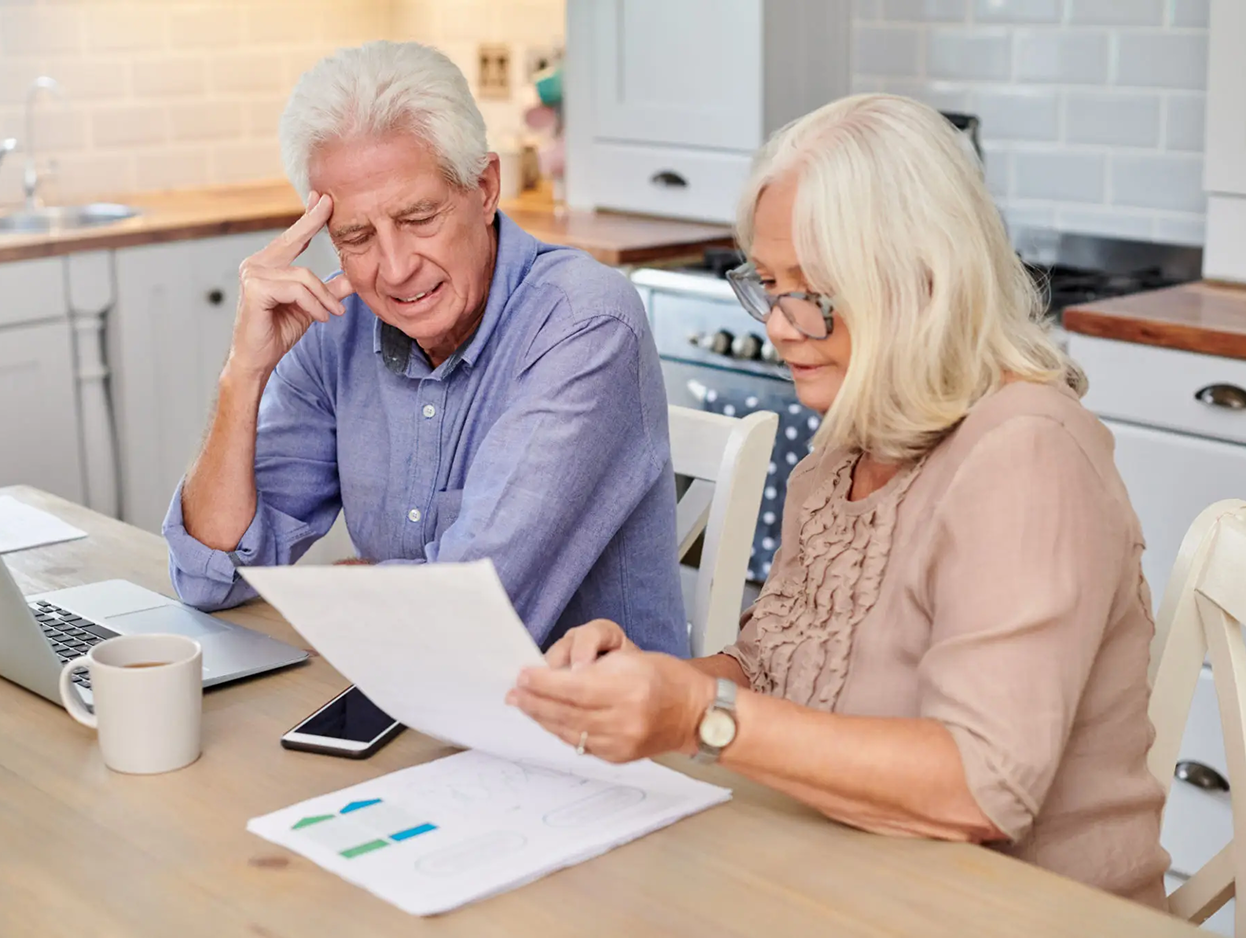 Older adults discussing paperwork in kitchen