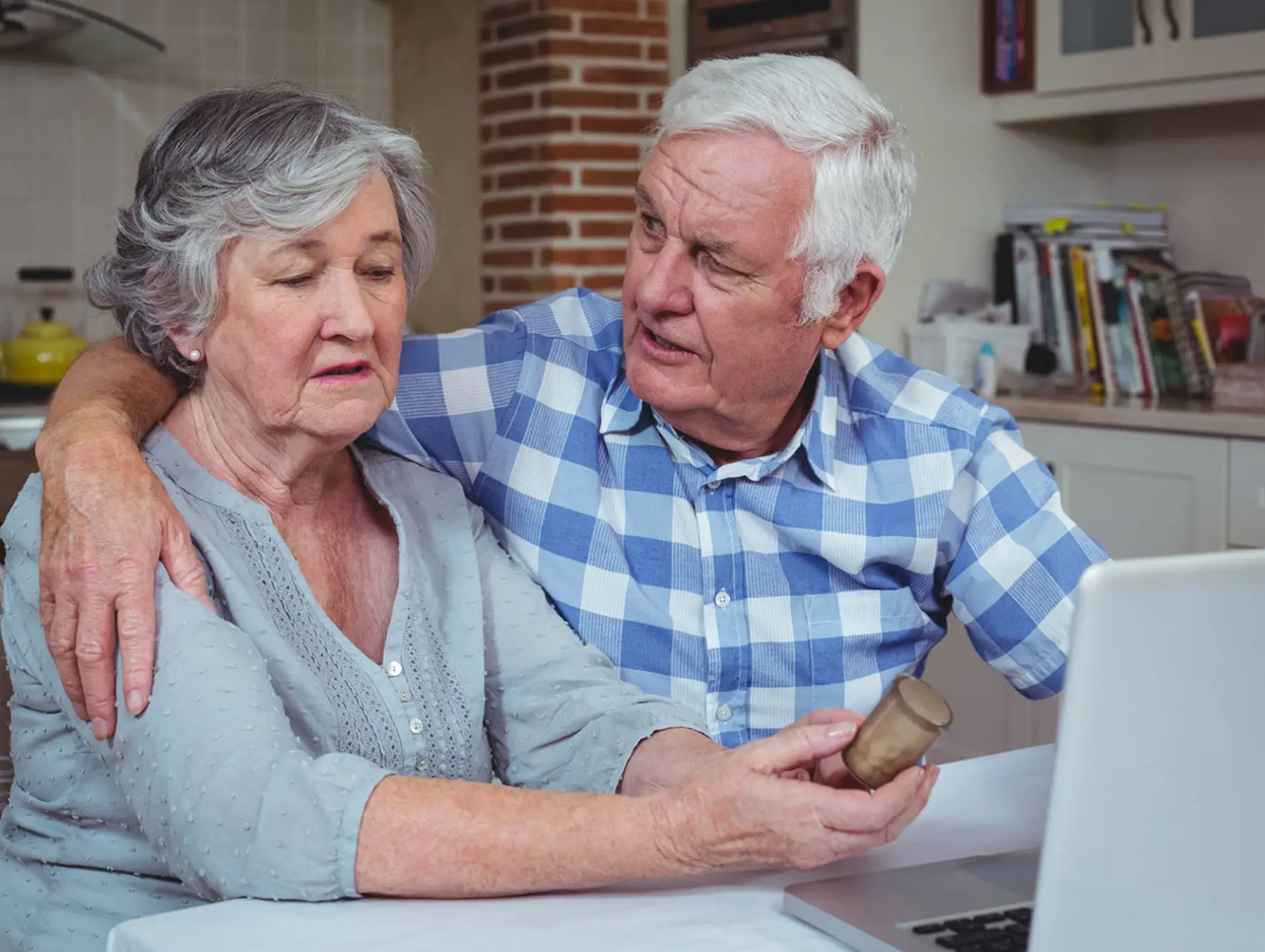 Senior couple with laptop and medicine bottle