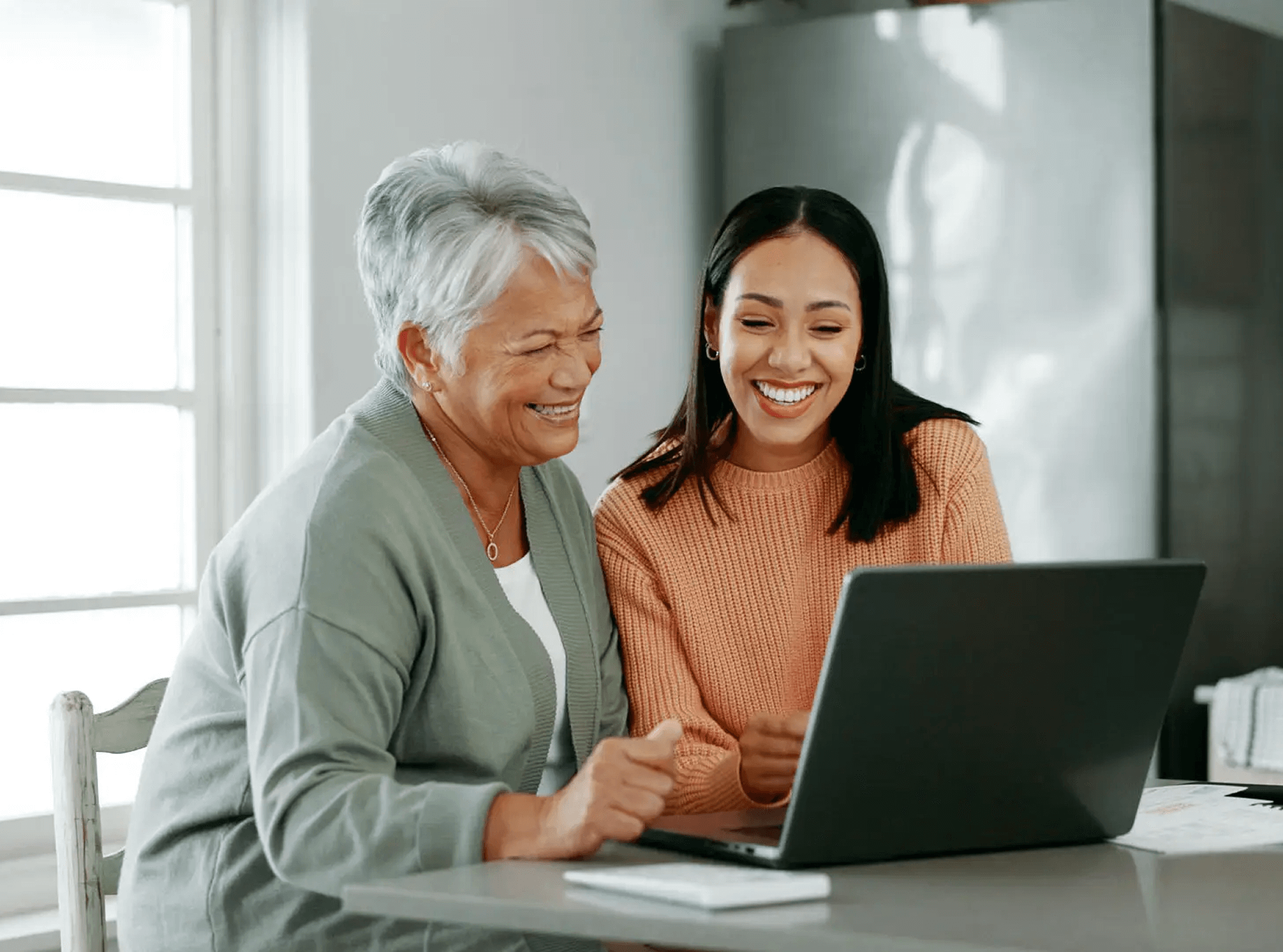Two women smiling at laptop screen