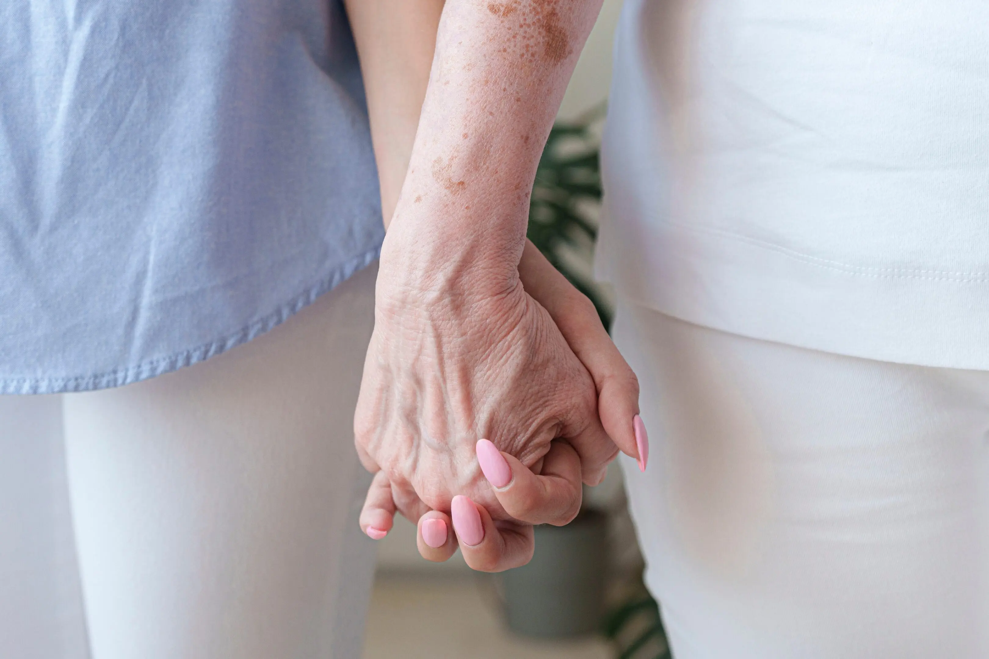 Two elderly people holding hands, showing care and connection.