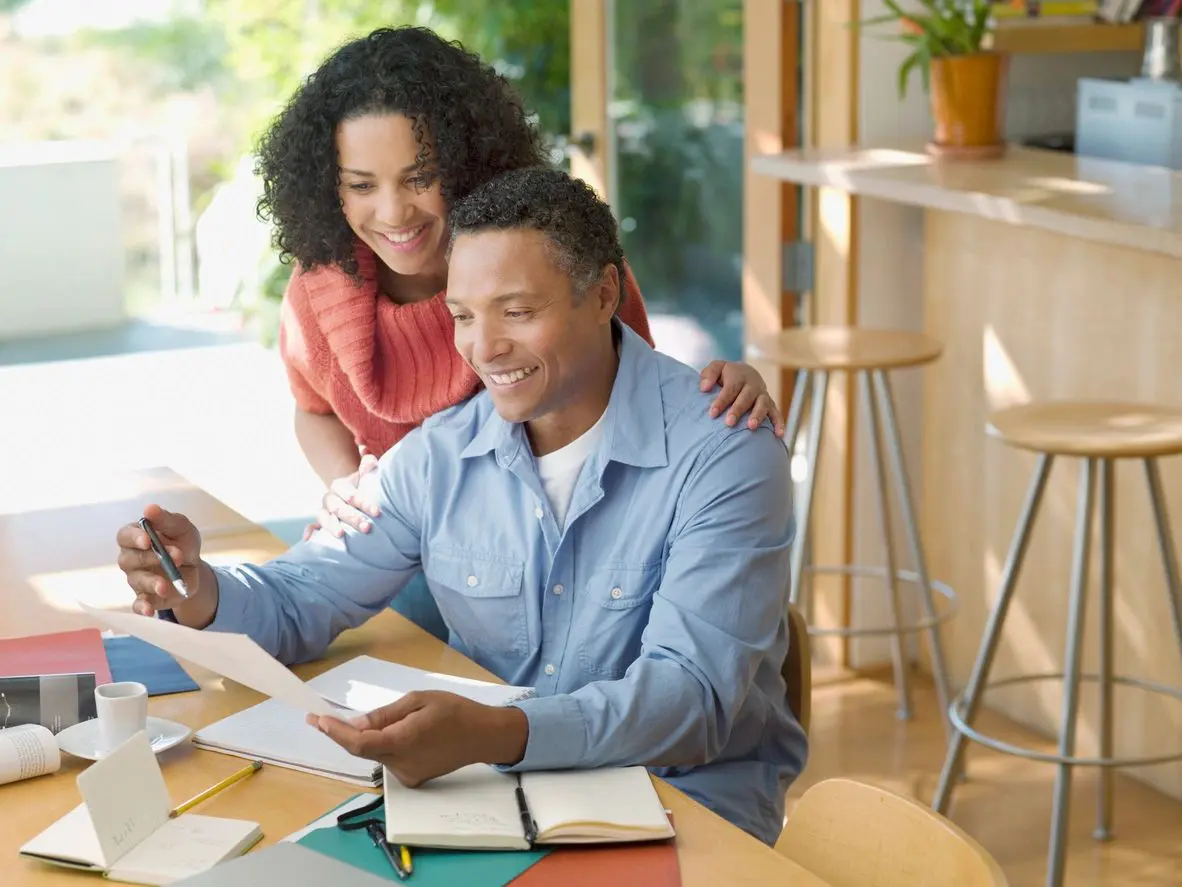 Smiling couple reviewing paperwork at home