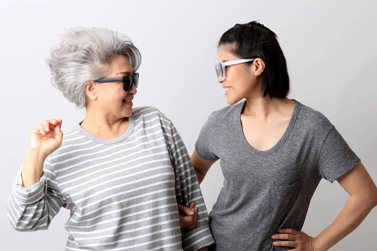 Two women wearing sunglasses smiling at each other