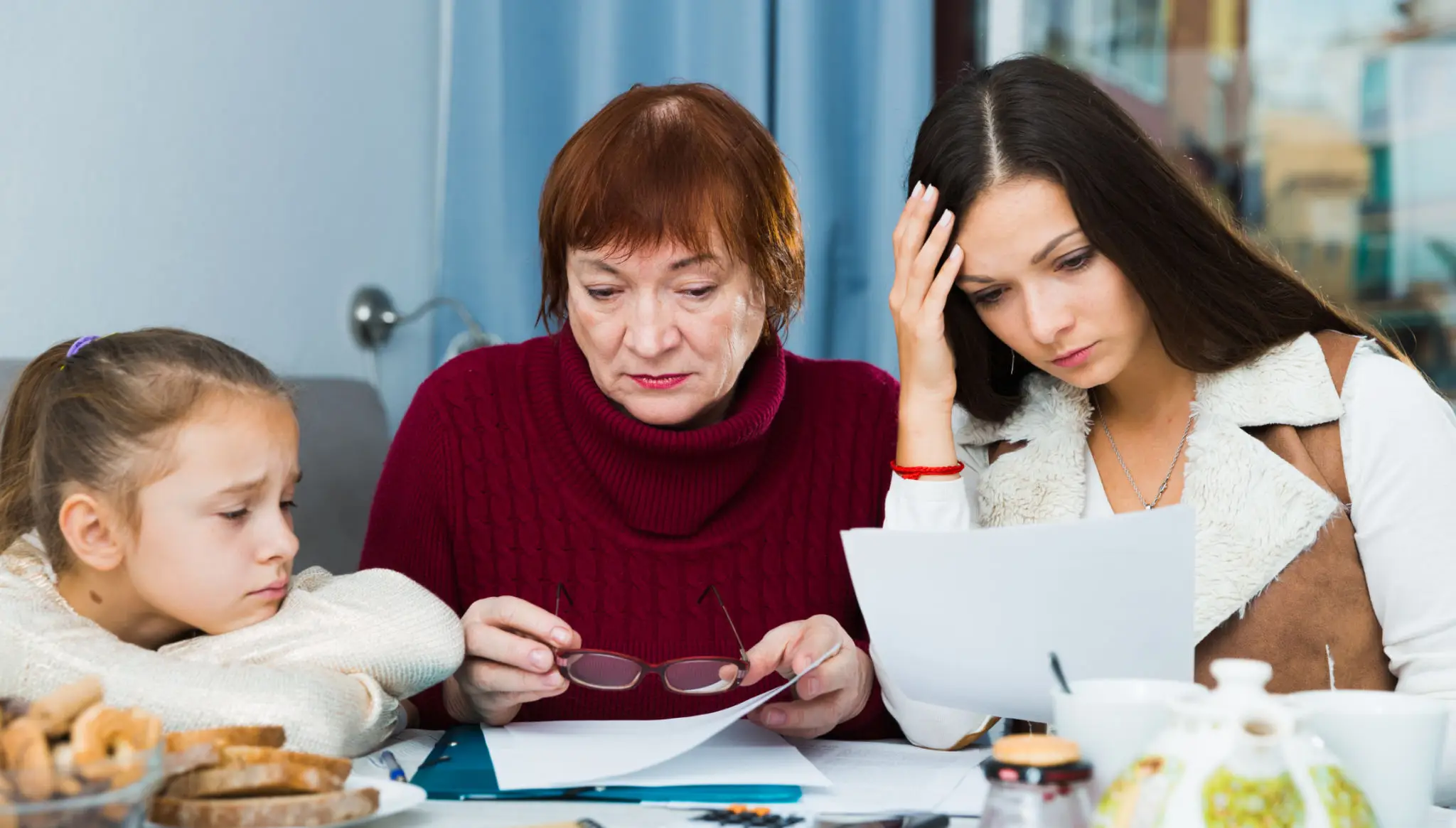 Two women reviewing financial documents with concern.