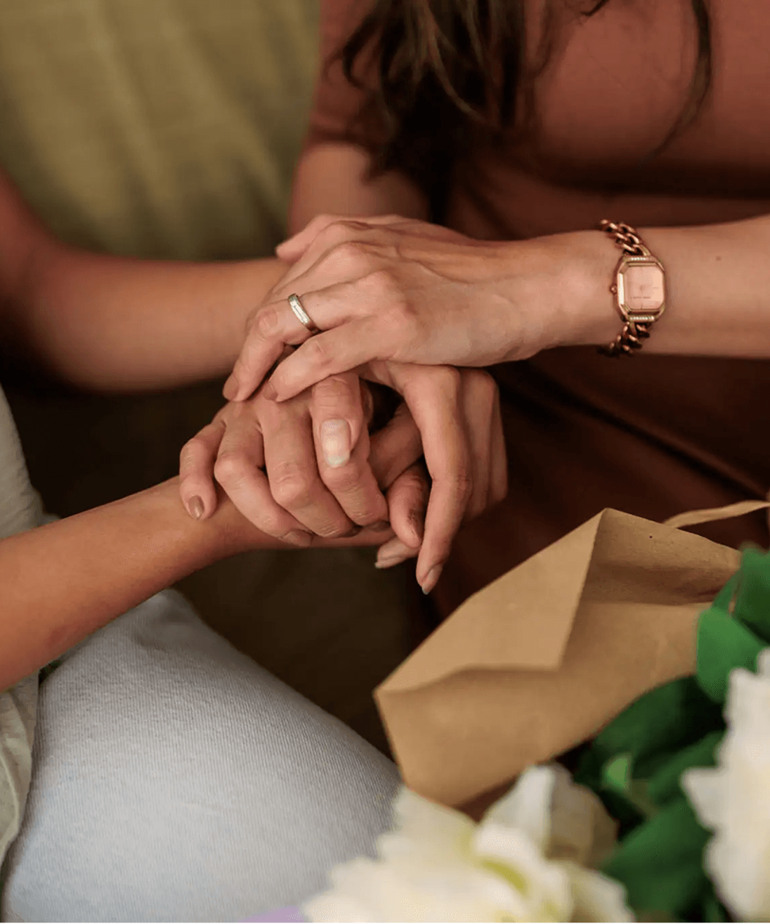 Close-up of two people holding hands, one wearing an engagement ring.